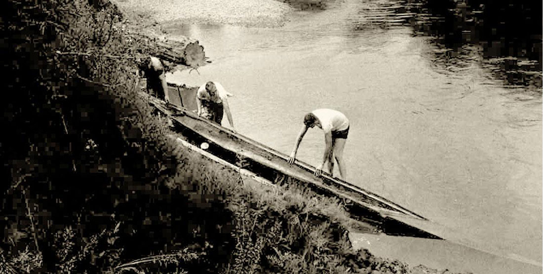 black and white photograph showing two men removing the canoe from the river in 1963