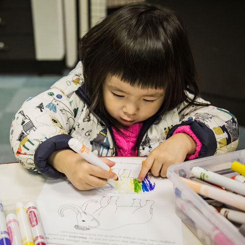 Youth & Families child coloring with markers in a coloring book