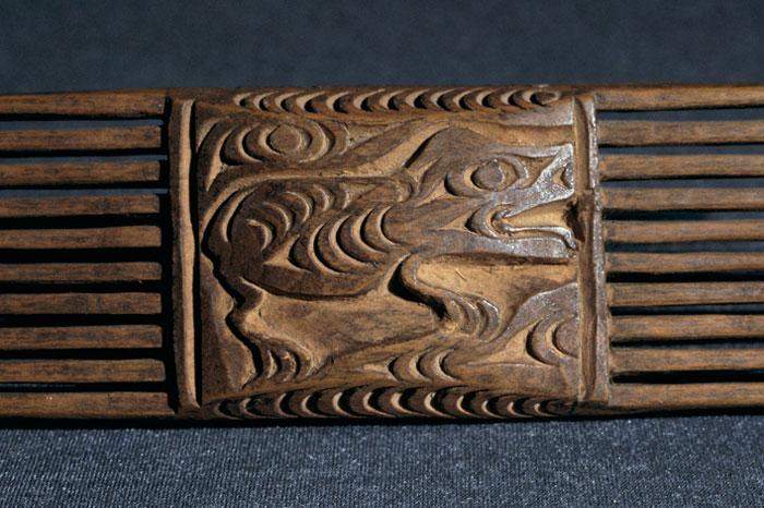 A comb with a creature depicted in a way that exaggerates their most identifiable features, with large heads, eyes, and snouts or beaks.